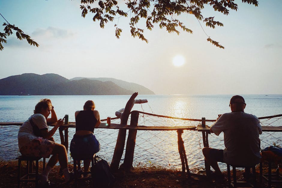 Three people enjoy a serene sunset view over the ocean