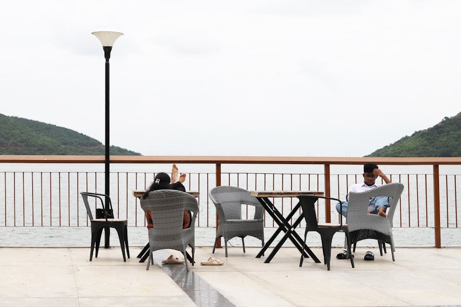 Two people relax on a waterfront terrace with scenic views
