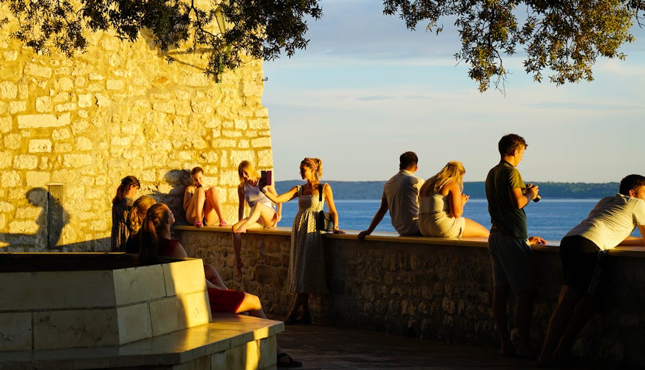 People relaxing on a seaside wall during golden hour in Rab, Croatia