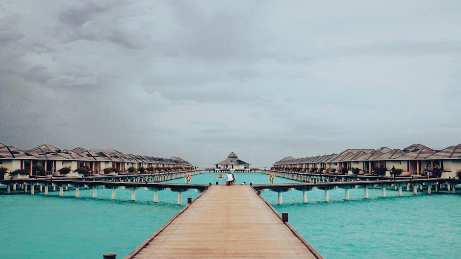Scenic view of wooden pathway leading to overwater villas in Maldives on a cloudy day