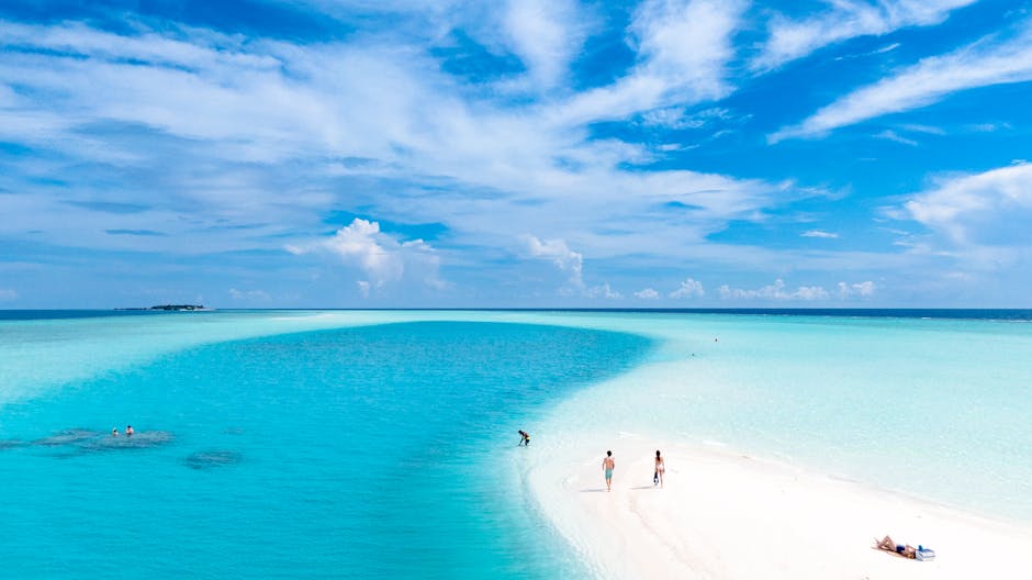 Turquoise waters and sandy beach in the Maldives during daylight with people relaxing and swimming