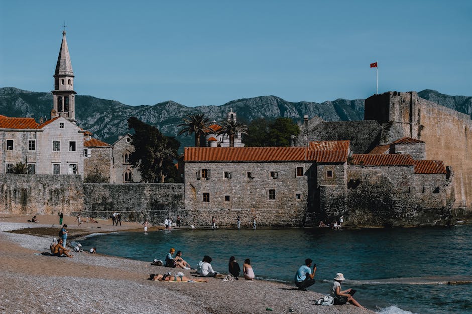 Sunny day at Budva Beach featuring the historic medieval town walls and mountains