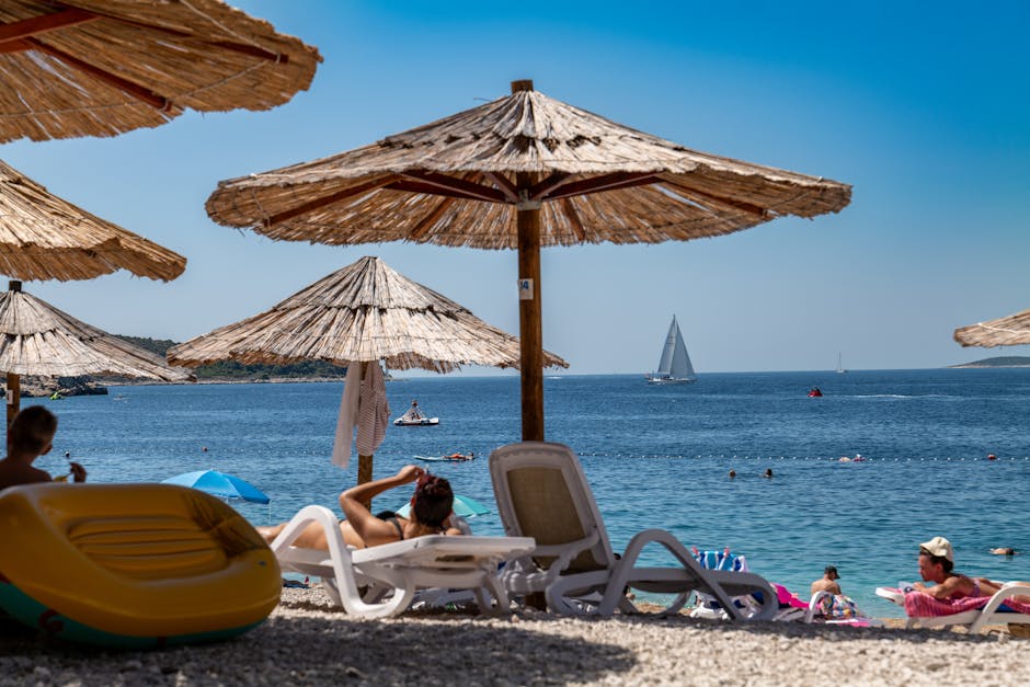 Relaxing beach scene with straw umbrellas and sunbathers in Primošten, Croatia