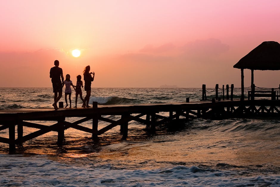 Silhouetted family enjoys a stroll on the beach pier at a vibrant sunset