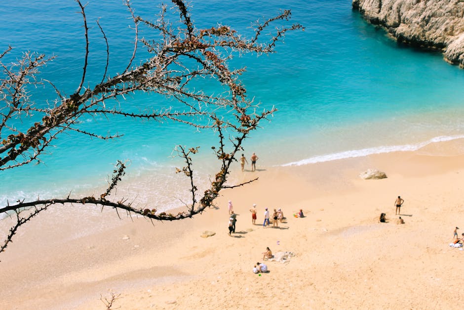 A beautiful beach scene with turquoise water, sand, and beachgoers enjoying a sunny day